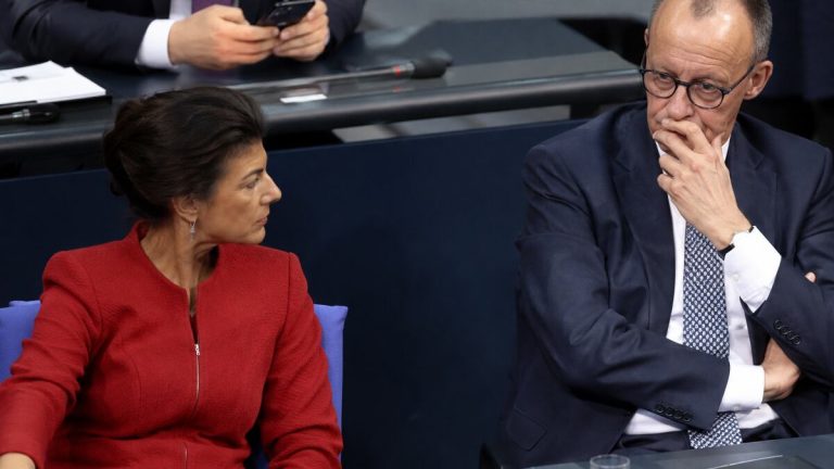 Sahra Wagenknecht w czerwonej marynarce obok Friedricha Merza w sali parlamentarnej – ilustracja AI