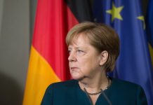„Nie wymyśliłam tego i nie podoba mi się”. Merkel krytykuje hasło „muru ogniowego” wobec AfD Angela Merkel na tle flag Niemiec i Unii Europejskiej