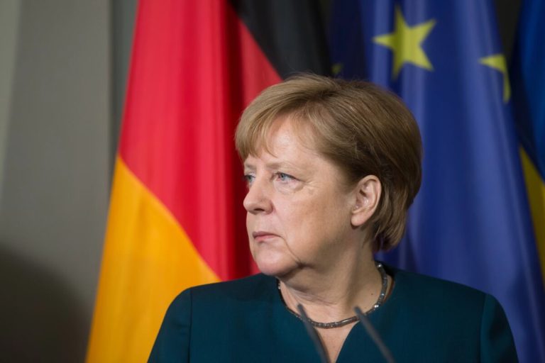 Angela Merkel na tle flag Niemiec i Unii Europejskiej