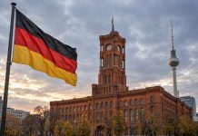 Unia grozi Berlinowi przymusem federalnym. Chce zablokować plany Lewicy dotyczące migracji! Niemiecka flaga przed Czerwonym Ratuszem i wieżą telewizyjną w Berlinie