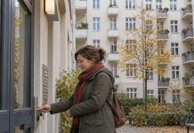 Lewica chce wywłaszczeń mieszkań w Berlinie! Dług ma być spłacany z czynszów Lokatorka otwiera drzwi budynku wielorodzinnego — ilustracja AI tematu mieszkań w Berlinie