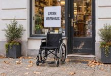 Berlin: nastolatkowie pobili 67-latka na wózku! Wywiesił plakaty przeciwko nienawiści do Żydów Ilustracja AI: pusty wózek przed sklepem i plakat przeciwko nienawiści do Żydów.