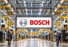 Bosch chce zlikwidować 900 miejsc pracy w Norymberdze. To połowa załogi zakładu! Ilustracja AI: duży znak Bosch pośrodku hali produkcyjnej, dwie osoby z tyłu; nie przedstawia rzeczywistego zakładu w Norymberdze