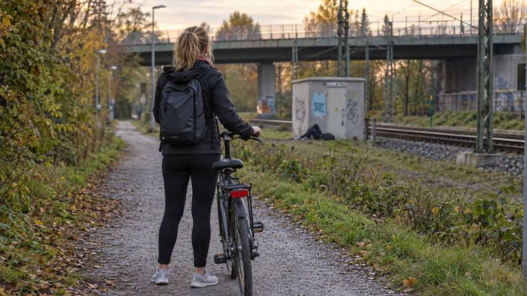 Ilustracja AI: rowerzystka na ścieżce przy torach kolejowych w Niemczech