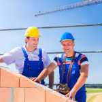 Construction site workers building house with crane
