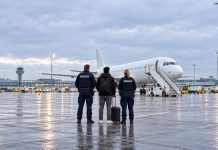 W Niemczech nie wykonano ponad 14 tys. planowanych deportacji! Rząd nie zna dokładnych przyczyn Symboliczna ilustracja AI: podróżny i funkcjonariusze Bundespolizei na lotnisku, przed samolotem