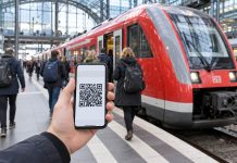 Niemcy: Deutschlandticket znów drożeje. Od stycznia będzie kosztować 66,80 euro miesięcznie! Telefon z biletem cyfrowym na tle czerwonego pociągu regionalnego w Niemczech