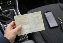 Dowód rejestracyjny w Niemczech: oryginał czy aplikacja? Dłoń trzymająca dowód rejestracyjny, obok telefon i kluczyki na fotelu samochodu
