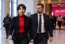 Liderka Lewicy w Berlinie potrzebuje ochrony na zjeździe własnej partii! Symboliczna ilustracja AI: Elif Eralp i fikcyjny funkcjonariusz ochrony w foyer spotkania Lewicy