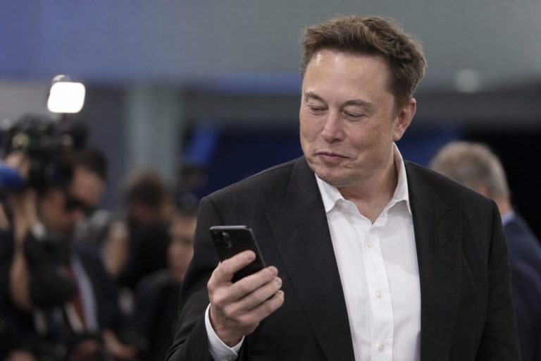 Elon Musk spoglądający na telefon podczas wydarzenia prasowego