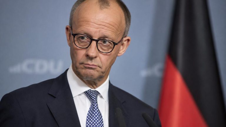 Friedrich Merz podczas wystąpienia na tle niemieckiej flagi