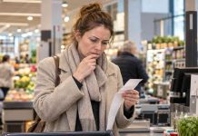 Gospodarka hamuje, ale ceny w Niemczech pozostaną wysokie! Bundesbank ostrzega Kobieta podczas zakupów w niemieckim supermarkecie analizuje rachunek przy kasie