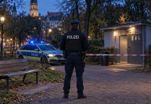 26-latka wykorzystana seksualnie w niemieckim parku. Policja opisała nawet fryzury poszukiwanych, ale pominęła kolor skóry! Ilustracja AI: policjant, radiowóz, ławka i budynek toalety w parku