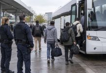 Migranci bez prawa pobytu mają trafić poza UE. Niemcy i cztery państwa szykują ośrodki powrotowe Grupa osób z bagażami wsiadająca do autobusu w obecności funkcjonariuszy