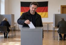 CDU traci 8 punktów w NRW! AfD już tylko 5 punktów za nią w nowym sondażu Symboliczna ilustracja AI: fikcyjny dorosły wyborca wrzuca czystą kopertę do urny w niemieckim lokalu wyborczym. Nie dokumentuje rzeczywistego głosowania.