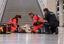 Nożownik zaatakował kobietę w monachijskim metrze! Ciężko ranna 49-latka runęła ze schodów Ilustracyjna scena: ratownicy pomagają dorosłej kobiecie u podnóża schodów w niemieckim metrze, obok policjant.