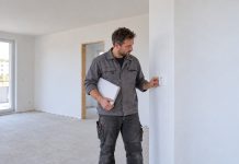 Mniej gniazdek i niższe sufity! Niemiecki rząd chce uprościć budowę mieszkań Pracownik sprawdza gniazdko w nowym mieszkaniu — ilustracja AI