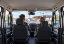 Pracujesz w Niemczech? Za dojazd do pracy może Ci się należeć nawet 428 euro więcej miesięcznie! Dwoje pracowników jedzie firmowym busem do zmiennego miejsca pracy w Niemczech – ilustracja