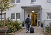 Azylanci powinni móc wyjechać z Saksonii-Anhalt. Turecka organizacja apeluje po wygranej AfD Symboliczna ilustracja zakwaterowania: osoba z bagażem przed ośrodkiem. Obraz wygenerowany przez AI.